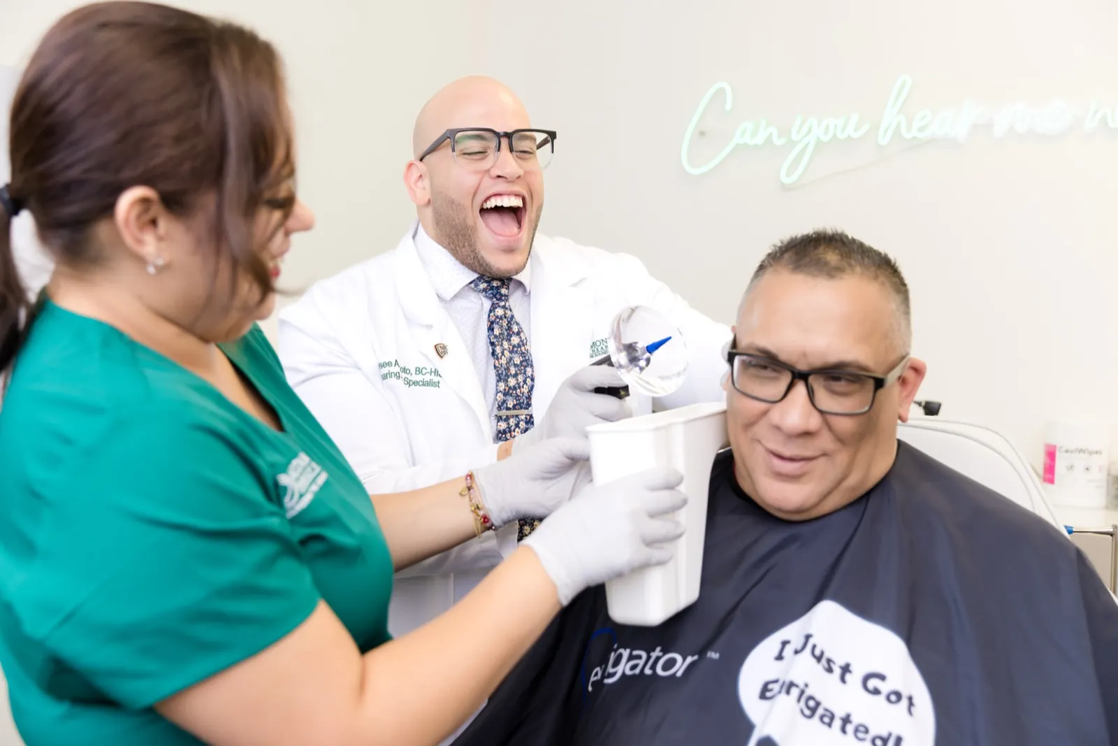 Jaysee using the Earigator on a patient wearing the clinic cape