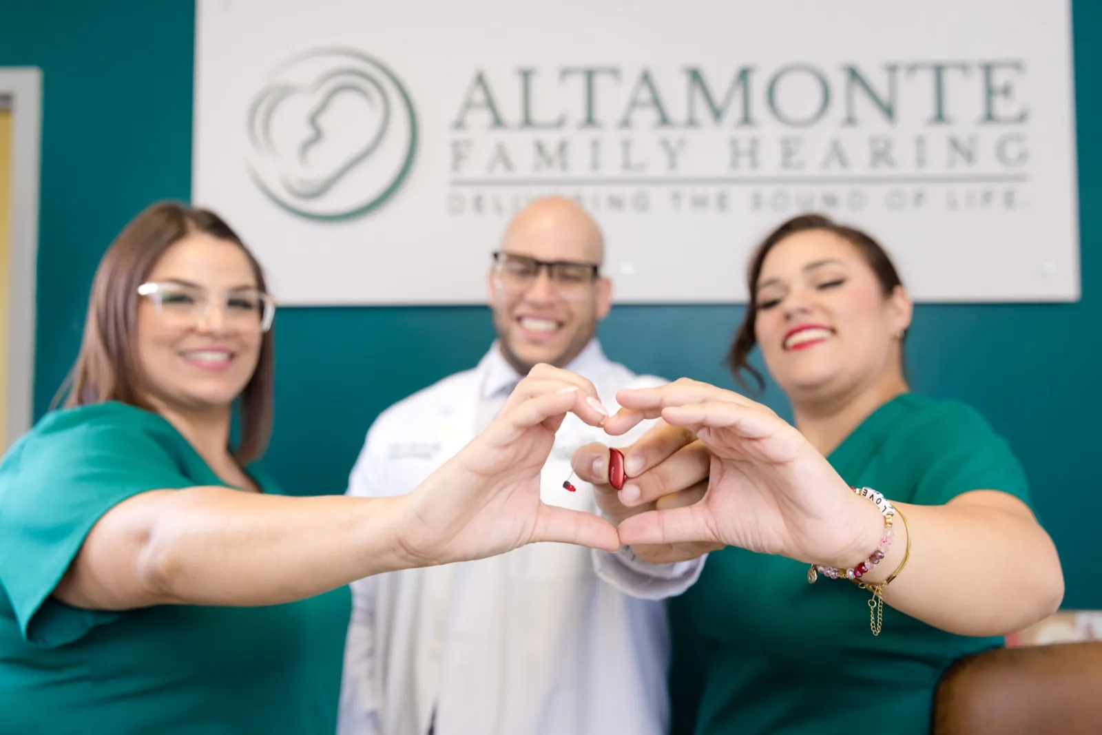 Grace, Jaysee and Francesca making a heart shape with their hands under the sign